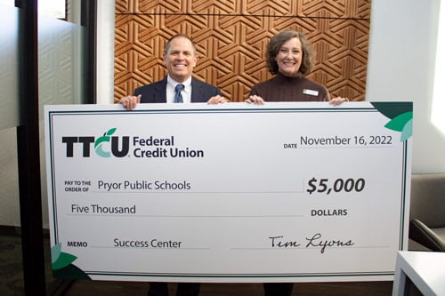 Two people holding large donation check